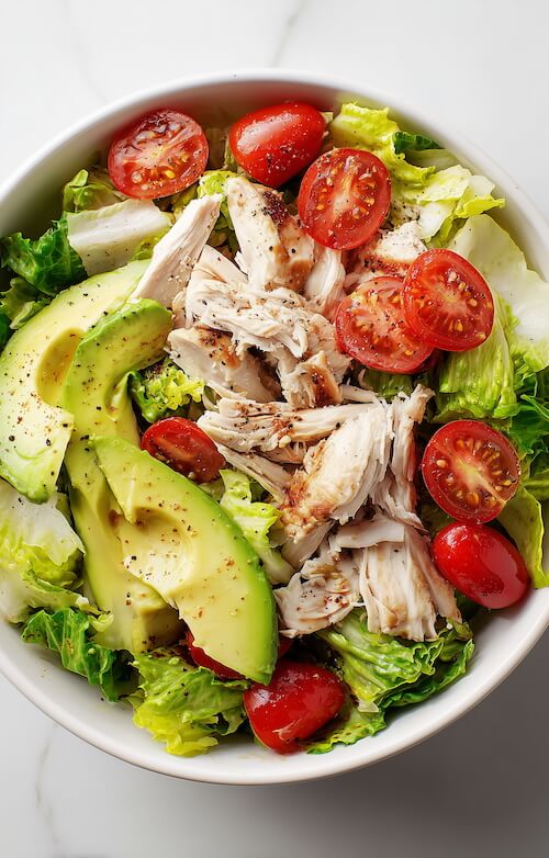 chicken-salad-with-lettuce-avocado-and-tomatoes-in-a-white-bowl